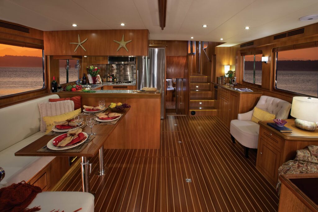 Luxurious wooden interior of a North Pacific yacht with dining area and kitchen at sunset