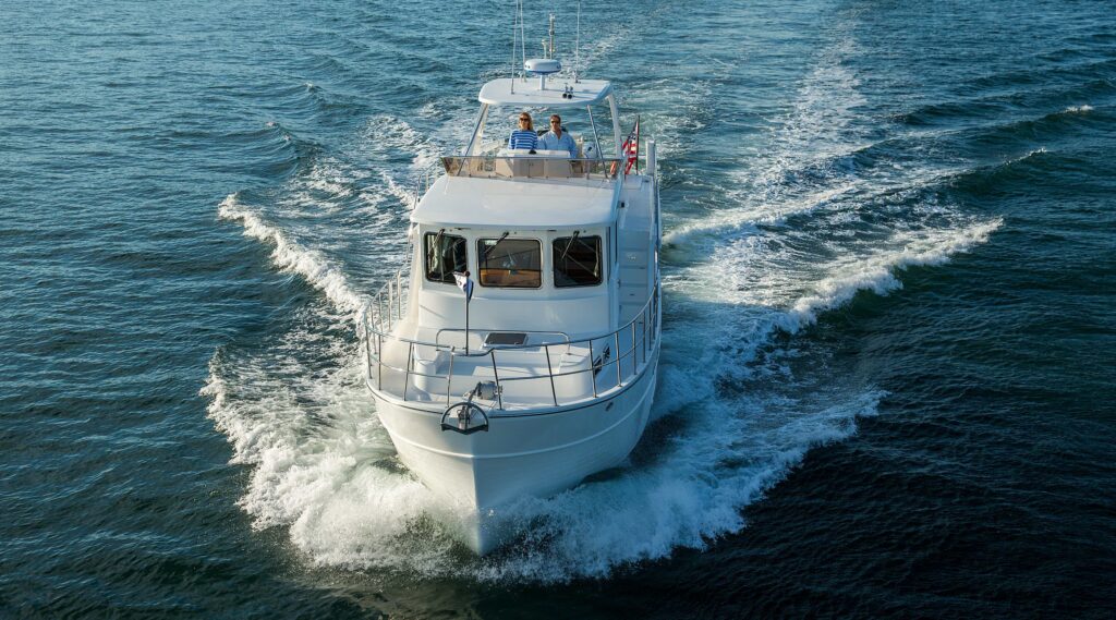 North Pacific custom pilothouse yacht cruising on open water with couple on flybridge