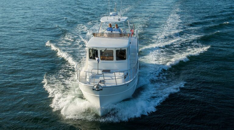 North Pacific custom pilothouse yacht cruising on open water with couple on flybridge