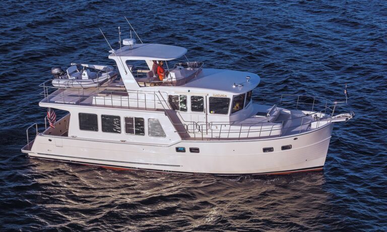 Side view of a white custom North Pacific pilothouse yacht cruising on calm waters