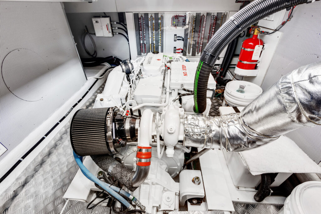 Clean white marine engine with advanced piping and fire extinguisher in yacht engine room