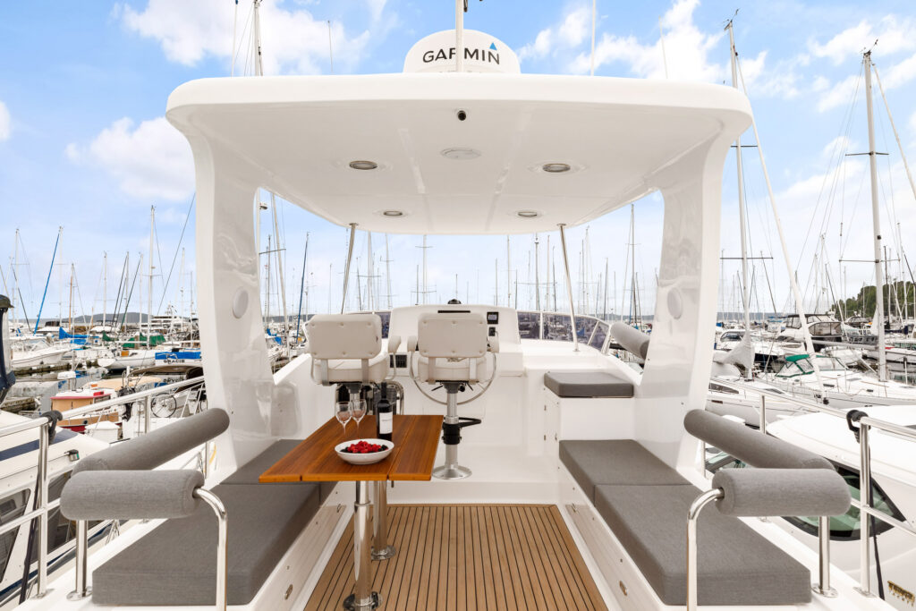 Spacious flybridge with seating and helm station on luxury trawler yacht in marina