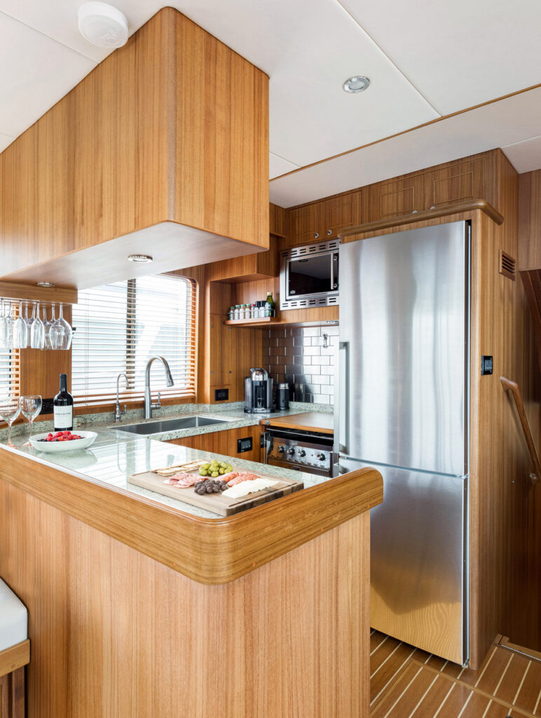 Modern yacht galley with stainless steel refrigerator and wooden cabinetry