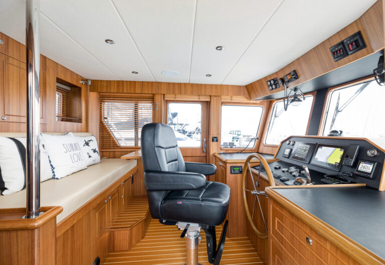 North Pacific Yacht pilothouse with black captain's chair, wood paneling, and navigation instruments