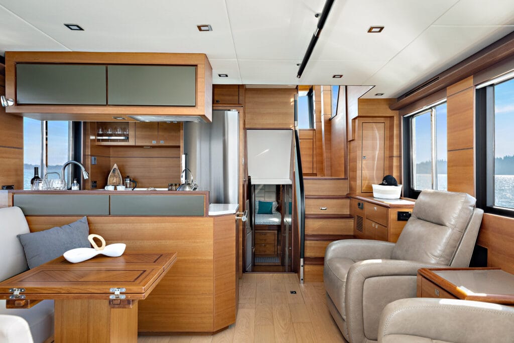 Luxurious wooden yacht interior with modern kitchen, comfortable seating, and ocean views