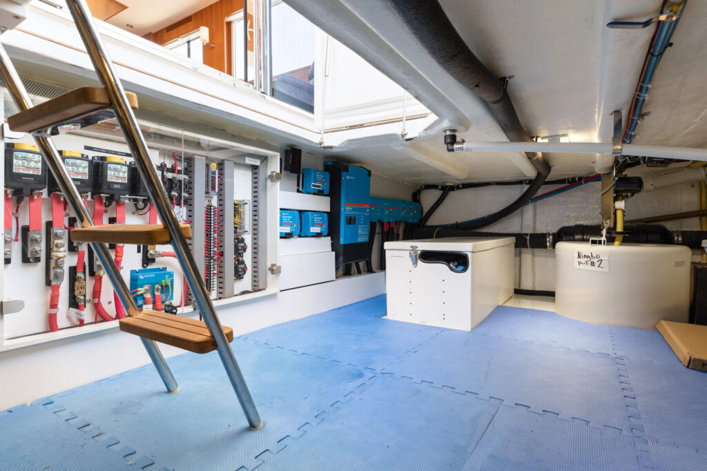 Spacious and organized boat engine room with electrical systems and ladder