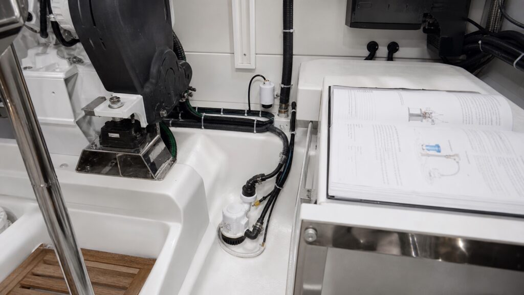 Representative bilge pump and separate high-water sensor with hoses, wiring, and an open manual